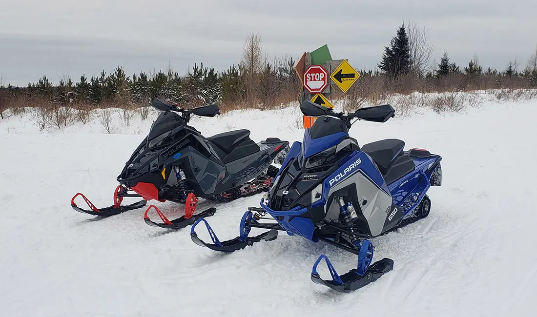 two snowmobiles in front of trees