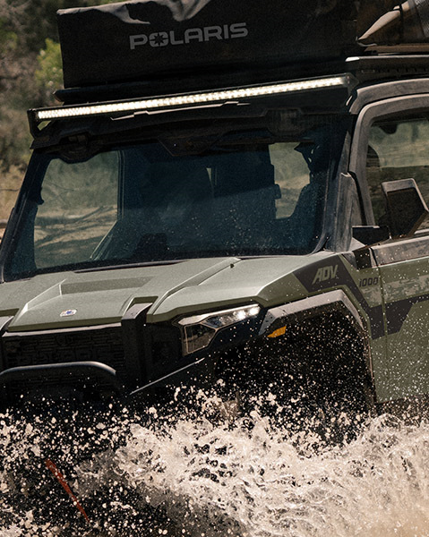 Front HD bumper, RIDIG 50-inch curved light bar, rooftop tent and Pro Armor Crawler XG Tires accessories from the Overland Package installed on a 2025 Polaris XPEDITION ADV 5 NorthStar side-by-side.