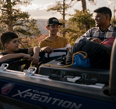 A family huddled around the cargo box of a 2025 Polaris XPEDITION XP side-by-side.