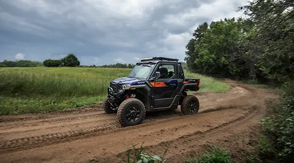 2 people on bikes riding away from a 2025 Polaris XPEDITION XP side-by-side with bike rack accessory installed.