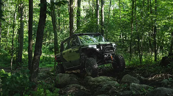 Front view of a 2025 Polaris XPEDITION XP 5 side-by-side cornering on a dusty trail.