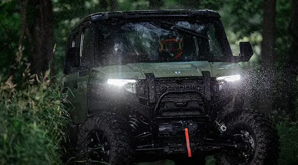 A couple loading firewood into the cargo box of their 2025 Polaris XPEDITION XP side-by-side.