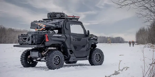 Side profile of a 2026 Polaris XPEDITION XP NorthStar side-by-side with 2 hunters walking away in the background.