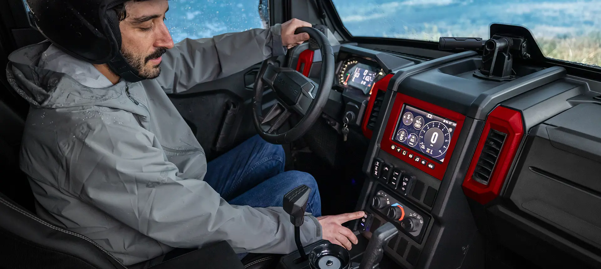 A man in a 2026 Polaris XPEDITION performance side-by-side using the windshield wiper switch.