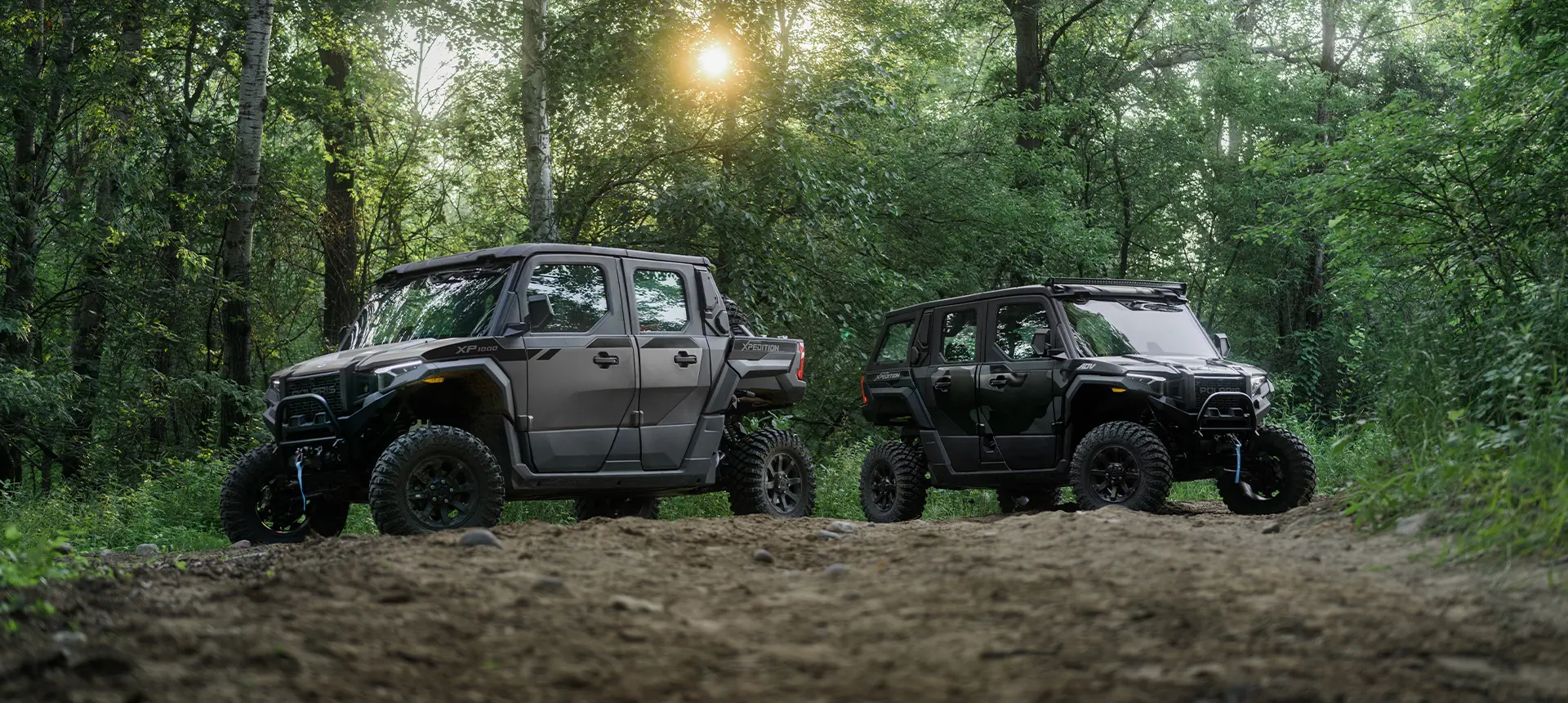 A 2026 Polaris XPEDITION XP 5 NorthStar side-by-side & a 2026 Polaris XPEDITION ADV 5 NorthStar side-by-side parked in forest.