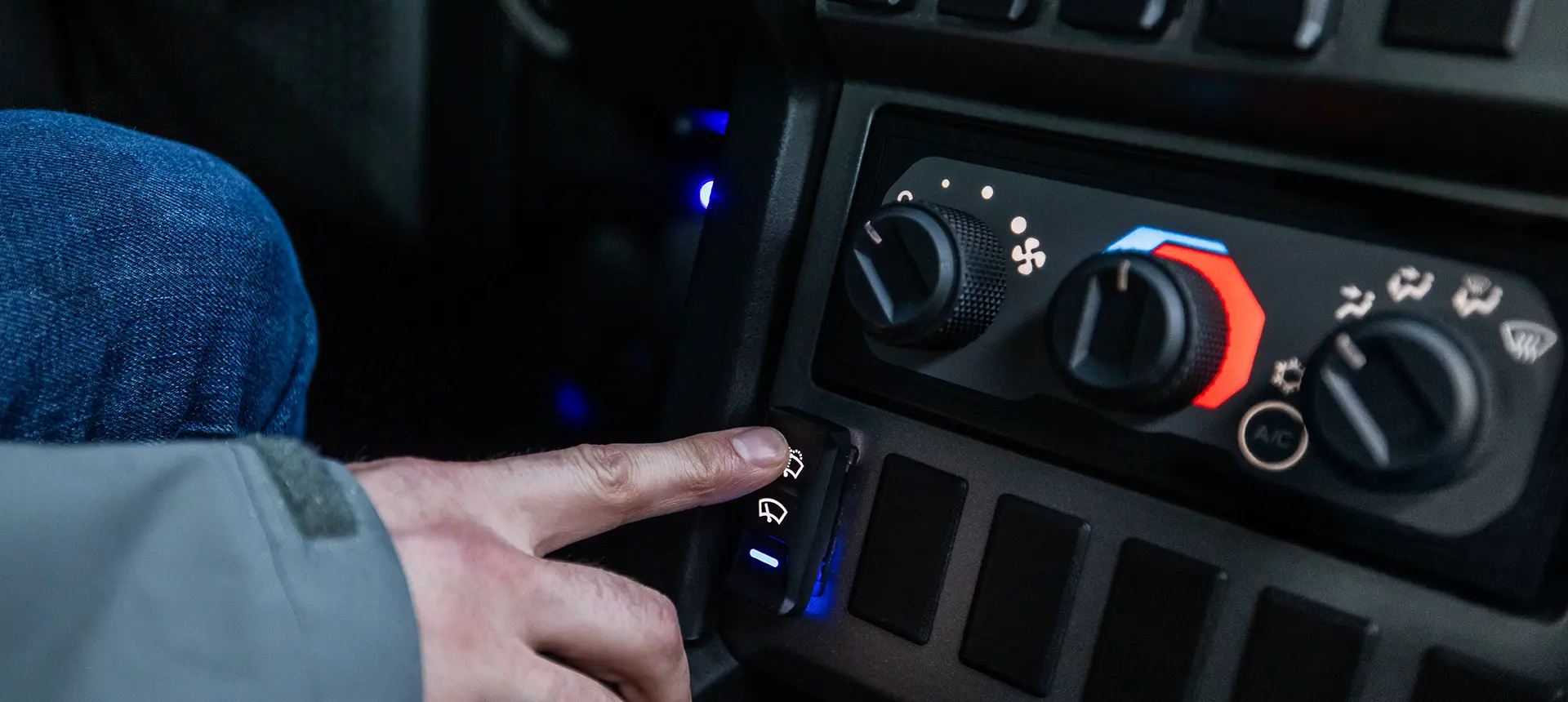 A person using the windshield wiper switch near the heat/ac controls inside of a 2026 Polaris XPEDITION performance SxS.