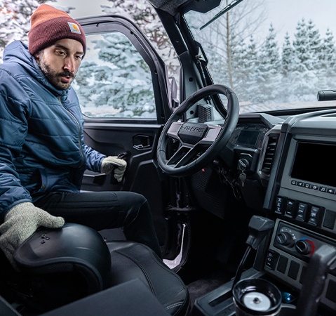 Man entering the enclosed cab of a 2026 Polaris XPEDITION ADV SxS.