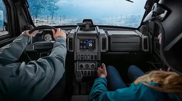 2 people inside of the all-season cab of a 2026 Polaris XPEDITION ADV NorthStar performance side-by-side.