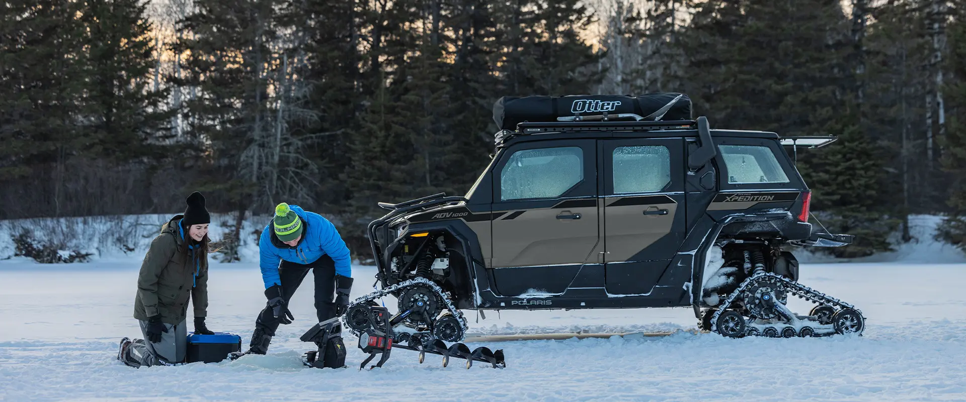 Deux personnes pêchant sur la glace avec leur VCC haute performance Polaris XPEDITION ADV NorthStar 2026 équipé de chenilles stationné en arrière-plan.