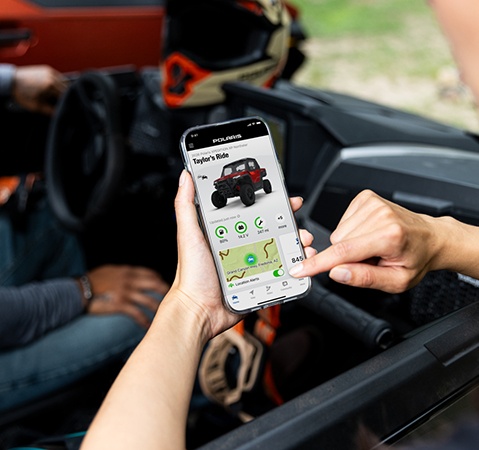 Person using the RIDE COMMAND app on a smartphone while in a 2026 Polaris XPEDITION XP NorthStar SxS.
