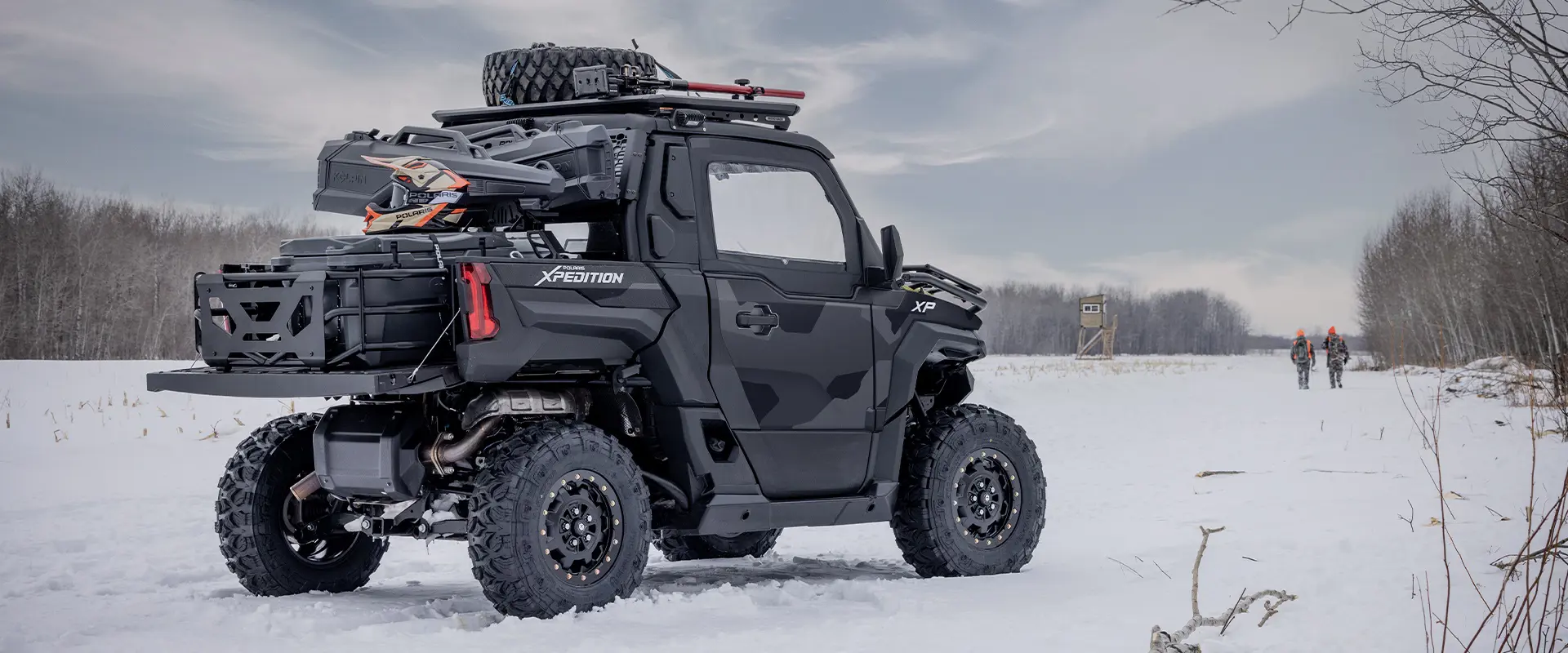 2 cazadores caminando de vuelta a su Side-by-Side Polaris XPEDITION XP NorthStar de 2026 en el invierno.