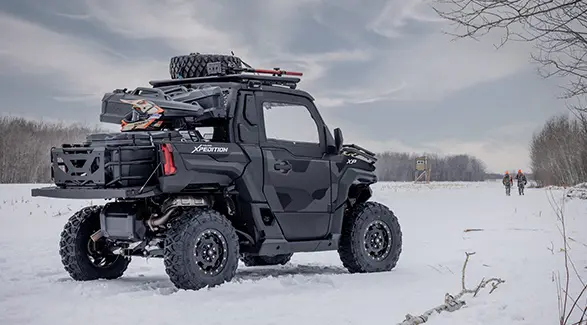 2 cazadores caminando de vuelta a su Side-by-Side Polaris XPEDITION XP NorthStar de 2026 en el invierno.