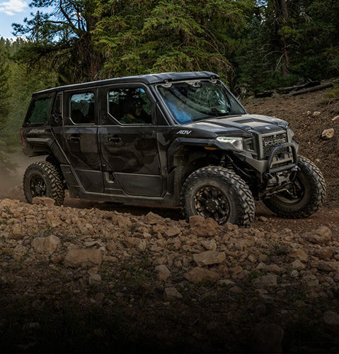 A 5 passenger Polaris XPEDITION ADV 5 enclosed cab side-by-side cruising on a trail.