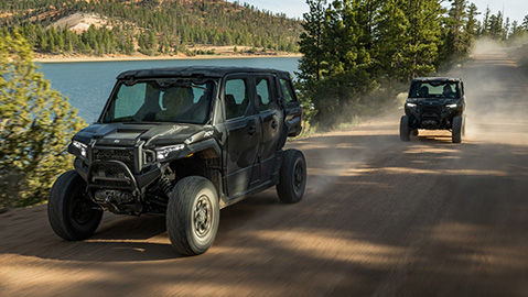 Two 2027 Polaris XPEDITION enclosed cab performance side-by-sides on a trail.