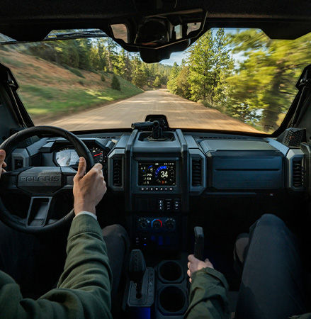 Over the shoulder view showcasing the dash and in-cab features of a 2027 Polaris XPEDITION ADV side-by-side.