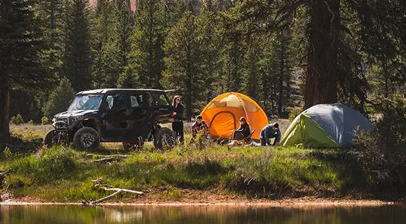 A person unloading gear from a 2027 Polaris XPEDITION ADV 5 NorthStar side-by-side.