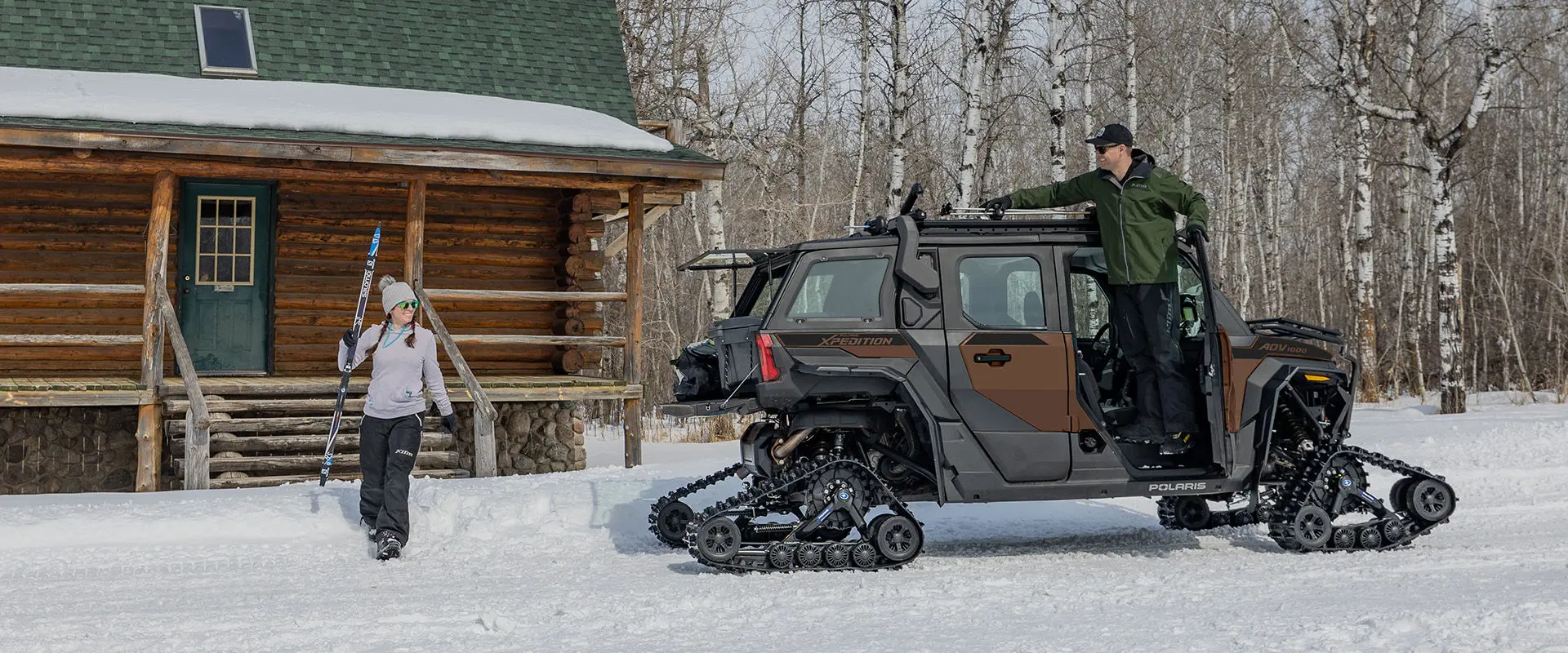 2 people gearing up to go skiing near a 2027 Polaris XPEDITION ADV 5 NorthStar side-by-side.