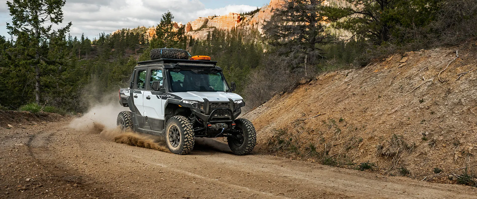 A rider cornering on a tight trail in the enclosed cab of a 2027 Polaris XPEDITION XP 5 NorthStar side-by-side.