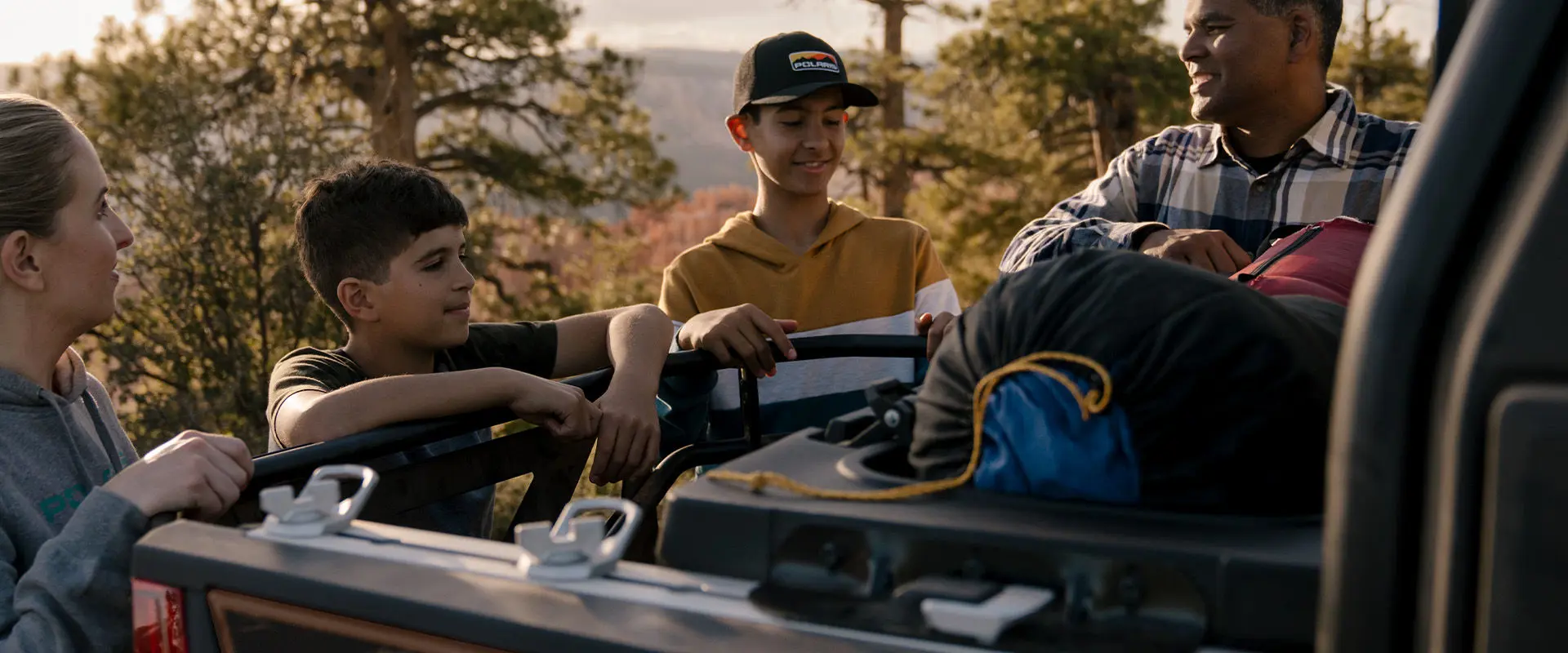 4 people standing around the cargo box of a 2027 Polaris XPEDITION XP 5 NorthStar side-by-side.
