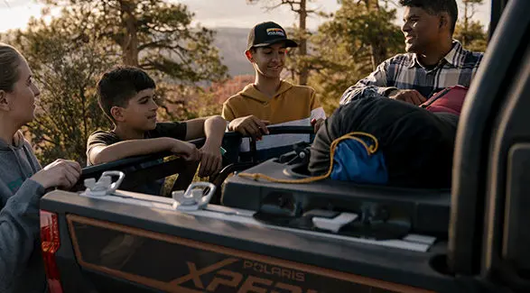 4 people standing around the cargo box of a 2027 Polaris XPEDITION XP 5 NorthStar side-by-side.