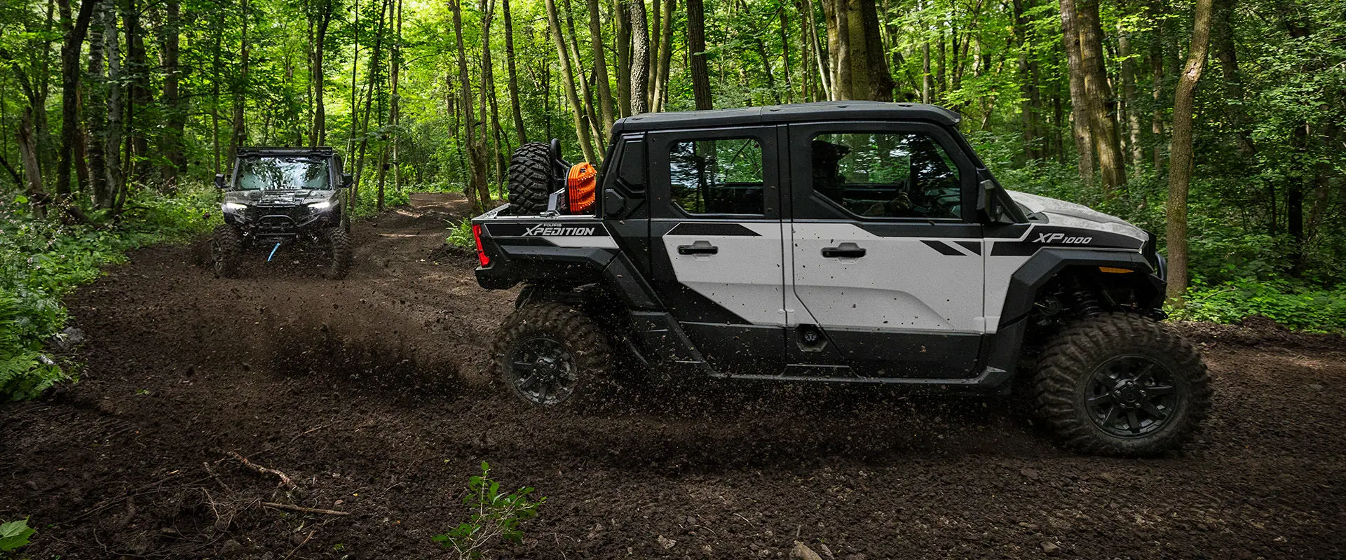 2 2027 Polaris XPEDITION XP NorthStar side-by-sides cruising down a forest trail.