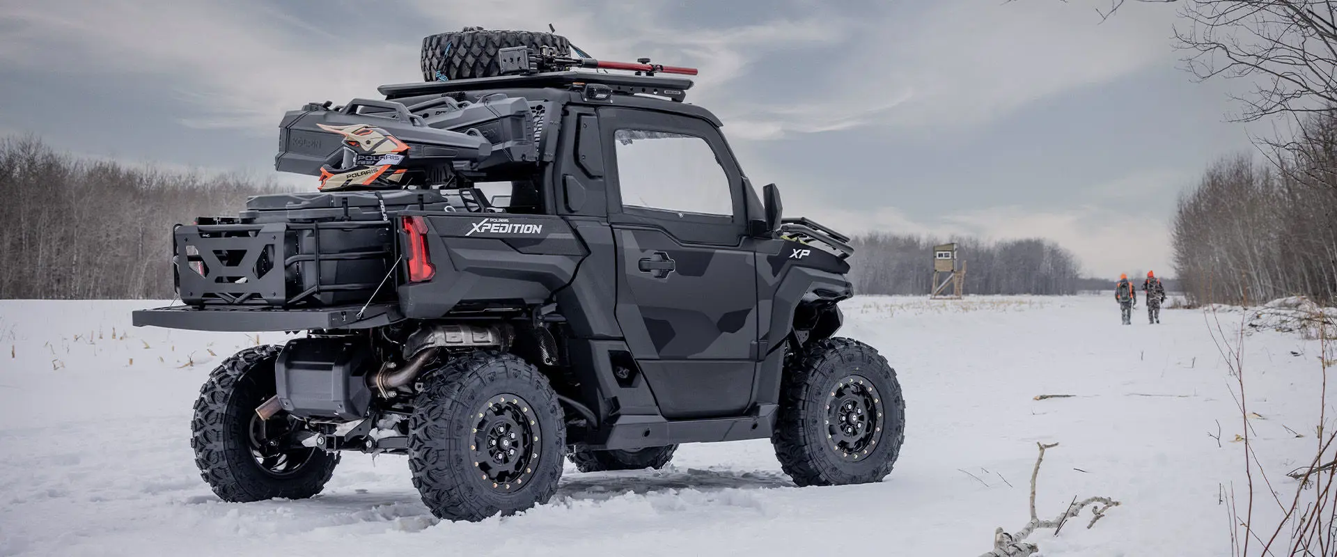 2 hunters in the winter walking away from a 2027 Polaris XPEDITION XP NorthStar side-by-side.