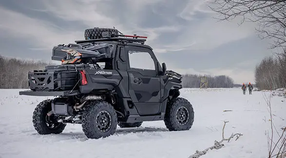 2 hunters in the winter walking away from a 2027 Polaris XPEDITION XP NorthStar side-by-side.
